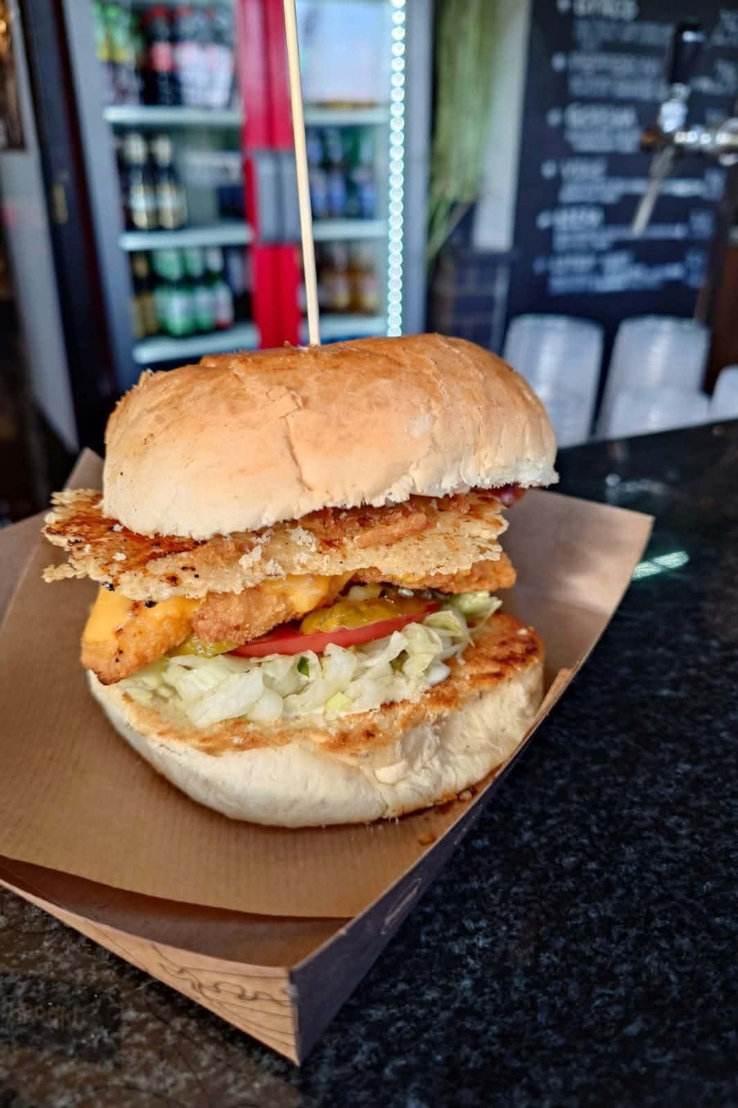 Burger z panierowanym filetem, pomidorem i sałatą