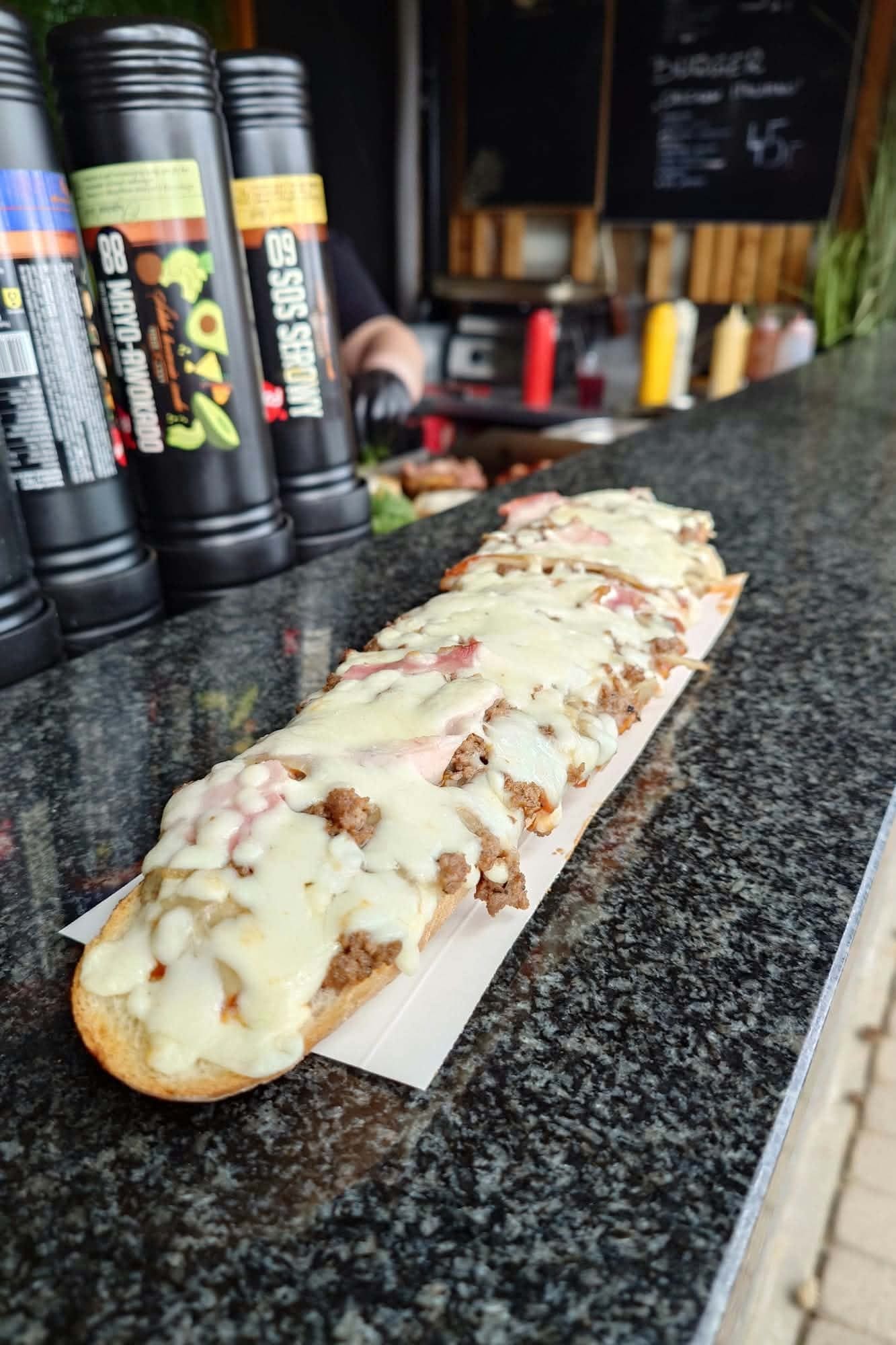 Zapiekanka z mięsem i serem przed butelkami sosów